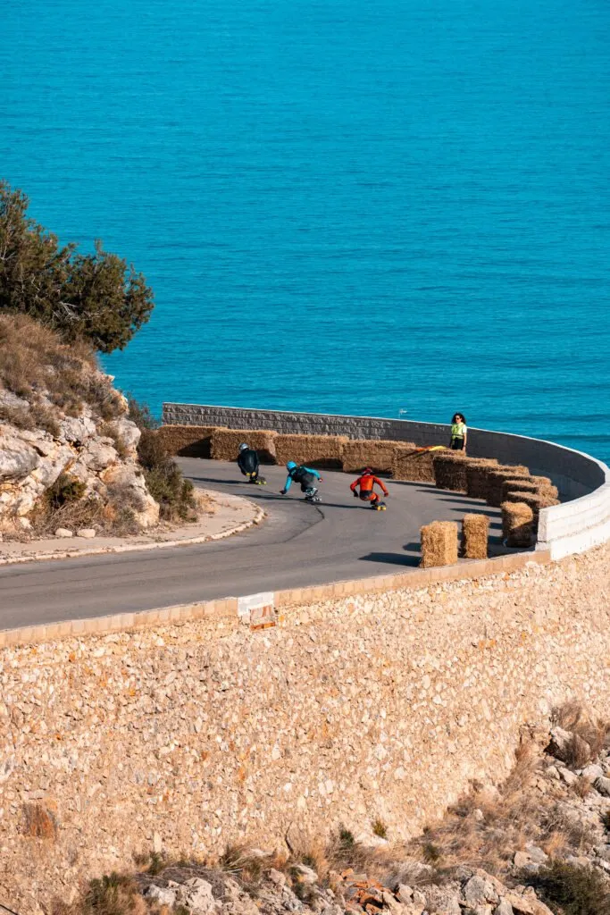 Riders de longboard tomando una curva sobre el Mediterráneo.